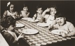 Toddlers at the La Pouponniere children's home in Belgium are seated around a table eating.