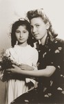 Two Jewish sisters who are living in hiding in Warsaw, pose for a formal portrait at the time of the younger girl's First Communion.