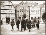 A small group of Jewish men, who have been rounded-up for arrest in the days after Kristallnacht, is escorted down a street by German police and SA members.