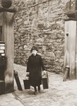 A  woman carrying two suitcases leaves her home during a round-up of local Jews for arrest in the days after Kristallnacht.