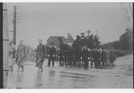 Father Bruno (Henri Reynders) leads a military funeral procession while serving as a chaplain in a prisoner of war camp.