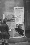 Two Polish boys read the posters and announcements that have been plastered on a pillar in Warsaw during the siege of the capital.