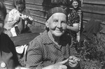 Portrait of an elderly, Jewish DP woman, who is knitting outside with a group of women at a displaced persons camp in Austria.