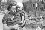 A Polish mother and child pose amidst the rubble on a street in Warsaw that had been bombed during the siege of the capital.