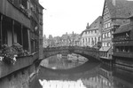 View of a bridge spanning a canal in Nuremberg.  The houses and bridge are bedecked with Nazi flags and banners.