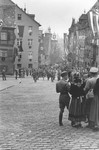 Uniformed Nazis congregate along a street in Nuremberg that is bedecked with Nazi banners [probably in celebration of the Reichsparteitag (Reich Party Day) of 1937].