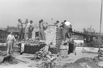 Under the guidance of an ORT instructor, Jewish DPs learn bricklaying by constructing a small brick building at a Jewish displaced persons camp in Linz.
