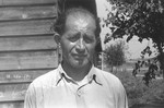 Portrait of a Jewish DP standing in front of a wooden barracks in a displaced persons camp in Austria.