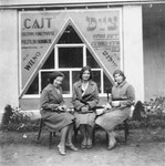 Three young Jewish women sit in front of the editorial office of the Yiddish daily newspaper, "Cajt."

Pictured from right to left are Raya Magid, her sister Katia Magid, and a friend, Nuta Klausner.