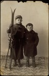 Studio portrait of two Jewish brothers, one holding a pair of skis.