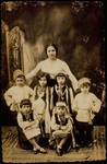 A Jewish teacher in Eisiskes poses with six kindergarten children dressed in costumes for a dance performance.