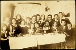 Young Jewish men and women pose around a table during a Saturday night party.