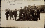 A school class gathers by a horse-drawn sleigh during a winter nature trip to the countryside.