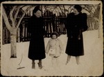 A young Jewish girl poses in the snow between her mother and her aunt.
