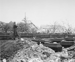 Tec Sgt. 4 James F. Flaha, of the 97th Infantry Division band, blows taps over the graves of prisoners murdered in the Flossenbuerg concentration camp.
