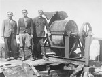 Jewish prisoners forced to work for a Sonderkommando 1005 unit pose next to a bone crushing machine in the Janowska concentration camp.