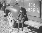 Joseph Schleifstein, a four-year-old survivor of Buchenwald, sits on the running board of an UNRRA truck soon after the liberation of the camp.