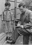 Joseph Schleifstein, wearing his old Buchenwald uniform, is interviewed by a journalist.