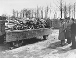 Three American radio journalists view a wagon full of corpses during a tour of the liberated Buchenwald concentration camp.