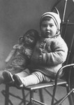 Studio portrait of a Jewish child posing on a chair with a doll in Sverdlovsk.