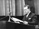 Alexander G. Hardy, Associate Counsel for the Prosecution, stands at the speaker's podium during a session of the Medical Case (Doctors') Trial in Nuremberg.
