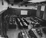 The defendants (left), their lawyers (center), the Military Tribunal I (right), and the prosecution (bottom), listen to the proceedings at a session of the Medical Case (Doctors') Trial in Nuremberg.
