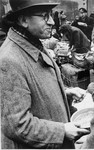 A man who has just arrived in Theresienstadt with a transport of Dutch Jews receives a bowl of food in the main courtyard of the ghetto.