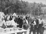 Prisoners involved in the construction of the camp queue up for food.