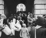 A large group of Dutch Jews who have just arrived in Theresienstadt are herded through a stone archway into the camp.