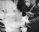 An elderly woman who has just arrived in Theresienstadt with a transport of Dutch Jews receives a bowl of soup.