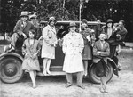 Frajda Fajerman (lower left) leans against an automobile surrounded by her factory coworkers.