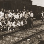 A group of young men and women from the Kloster Indersdorf DP children's center pose in front of a train before their departure.