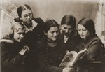 Felicja Berland (standing) looking at a book with school friends.