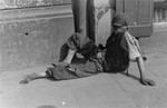 A destitute youth sits on the pavement in the Warsaw ghetto.
