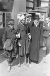A religious Jew stands with two destitute youth on a street in the Warsaw ghetto.
