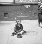 A destitute child begs on a street in the Warsaw ghetto.