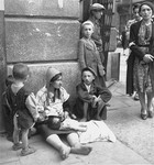 A destitute woman and her children on a street in the Warsaw ghetto.