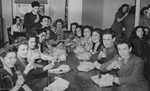 Refugee youth pose with milk bottles and bag lunches in a dining room at the Fort Ontario refugee shelter.
