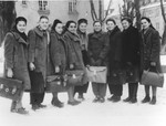 A group of teenage girls carrying briefcases pose on a snowy street on their way to their high school.