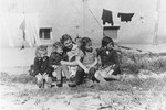 A group of children sit behind a barracks in the Ulm displaced persons camp.