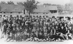 Group portrait of students in the Ulm displaced persons camp in front of their new school that is under construction.