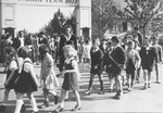 Jewish children walk hand-in-hand through the entrance to the Zeilsheim displaced person's camp during a Lag B'omer festival.