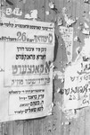 A notice advertising a concert of Yiddish music is posted on a wall in the Zeilsheim displaced persons' camp.