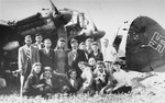 Group portrait of young Jewish DPs in front of a Nazi plane at an airport near Foehrenwald.