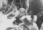 Young children eat a meal around a table in the preschool of the Zeilsheim displaced person' camp.