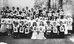 Group portrait of Polish children at their first communion holding pictures of Jesus.
