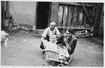 A Jewish family poses with a toddler in a stroller outside a barn.