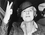 Portrait of Dorothy Thompson making a "V for Victory" sign and riding in a car.