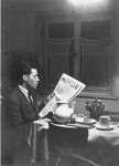 Solly Perel reads a newspaper in his room in Munich just prior to his departure for Palestine.