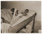 An emaciated female Jewish survivor of a death march lies in bed at an American military field hospital in Volary, Czechoslovakia.